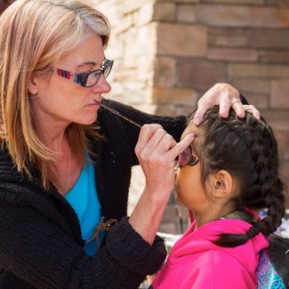 woman painting face of little girl