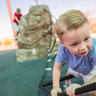 young boy playing on rope bridge