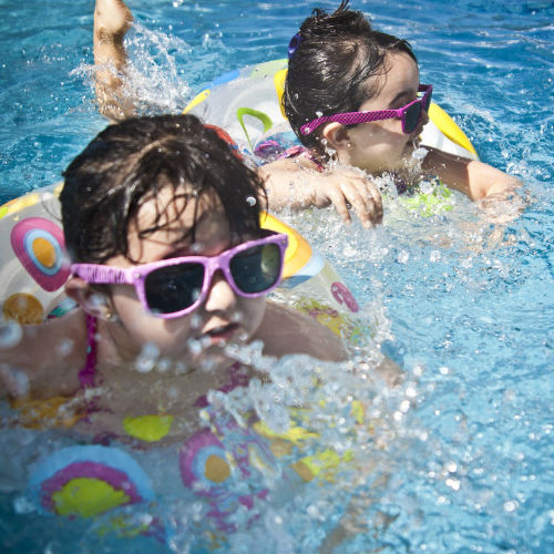 girls swimming in pool with floaties