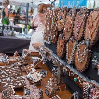 Colorful pieces of hand-crafted jewelry hang in a booth