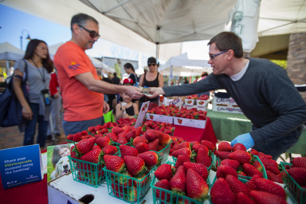 man selling strawberries at farmers market