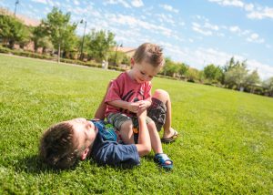 two young brothers playing in grass at park