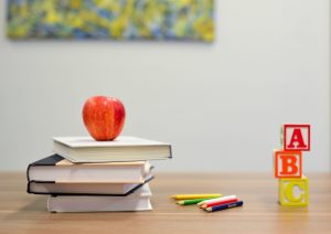 Letter blocks, books, and an apple decorate a preschool desk