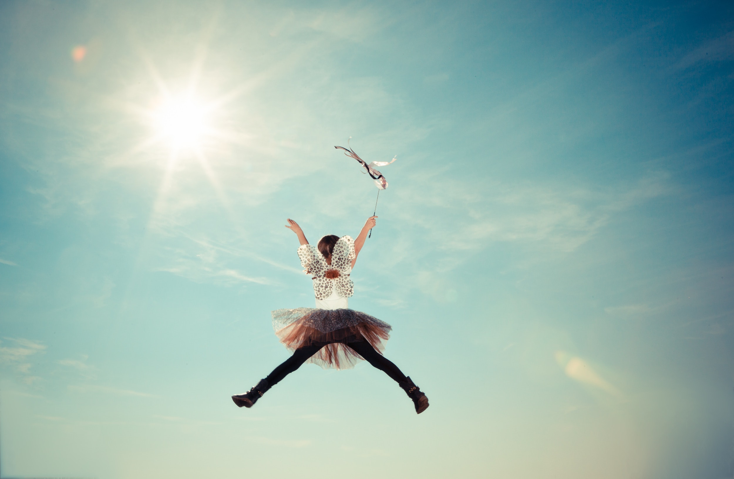 Child with fairy wings and skirt jumps into the air
