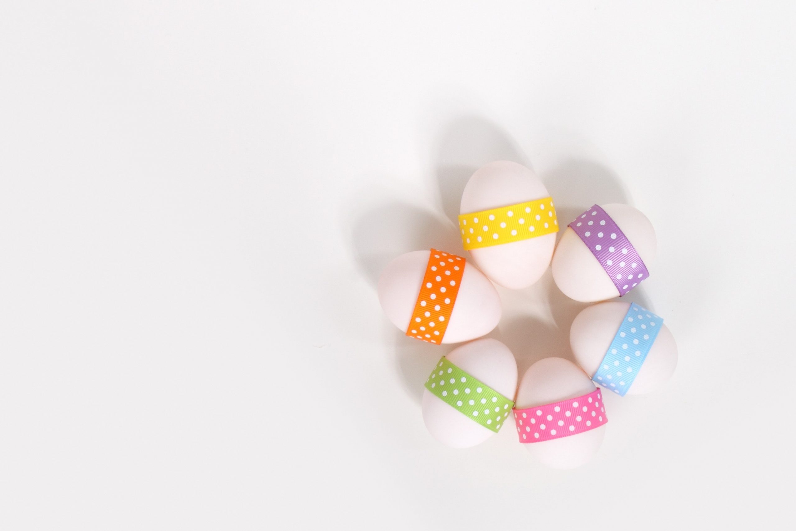 Three eggs have colorful ribbons with polka dots