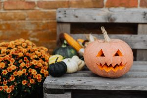 A carved pumpkin sits on a wooden bench