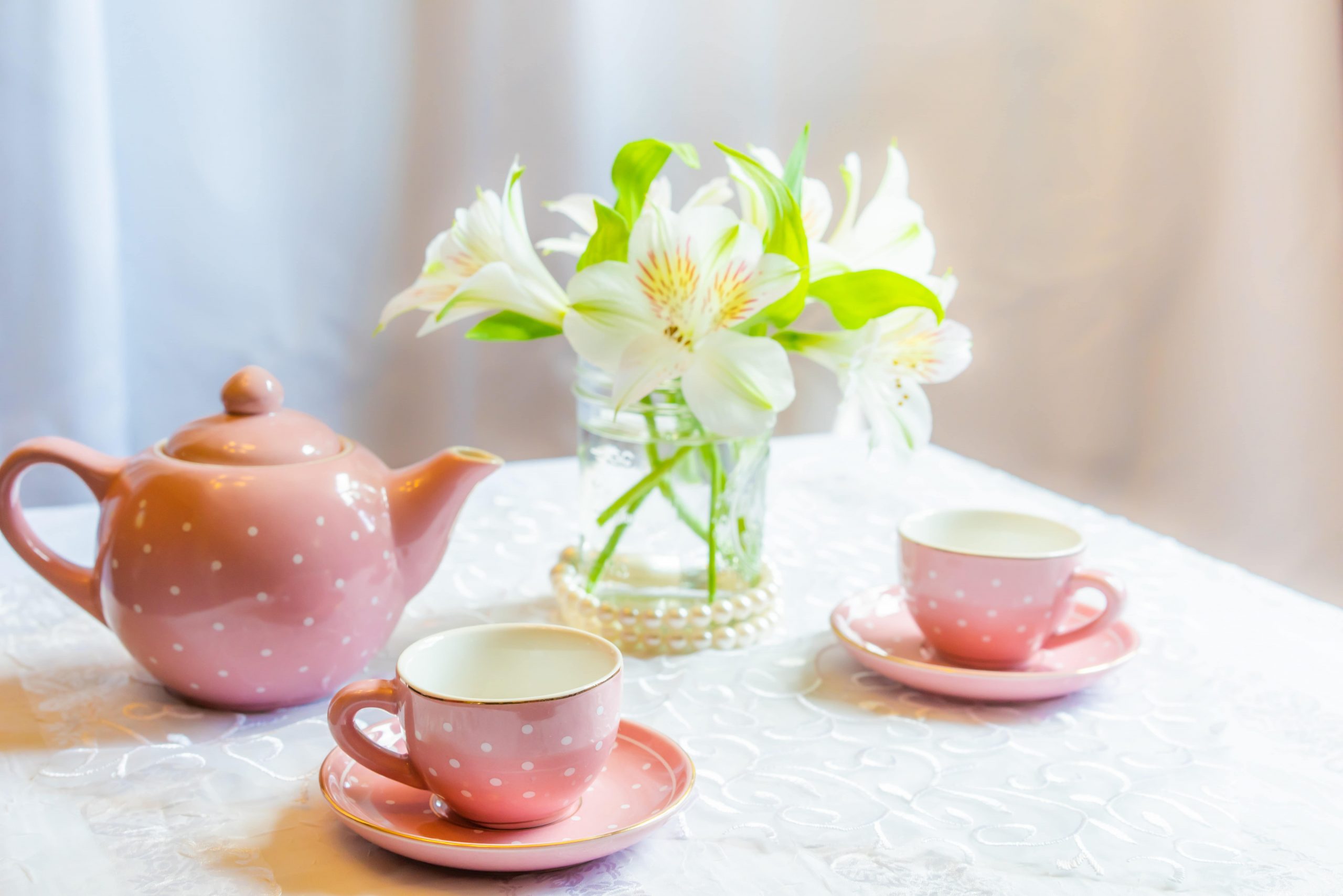 A pink tea pot and two pink cups