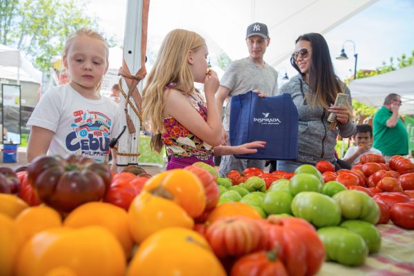 family buying vegetables at farmers market