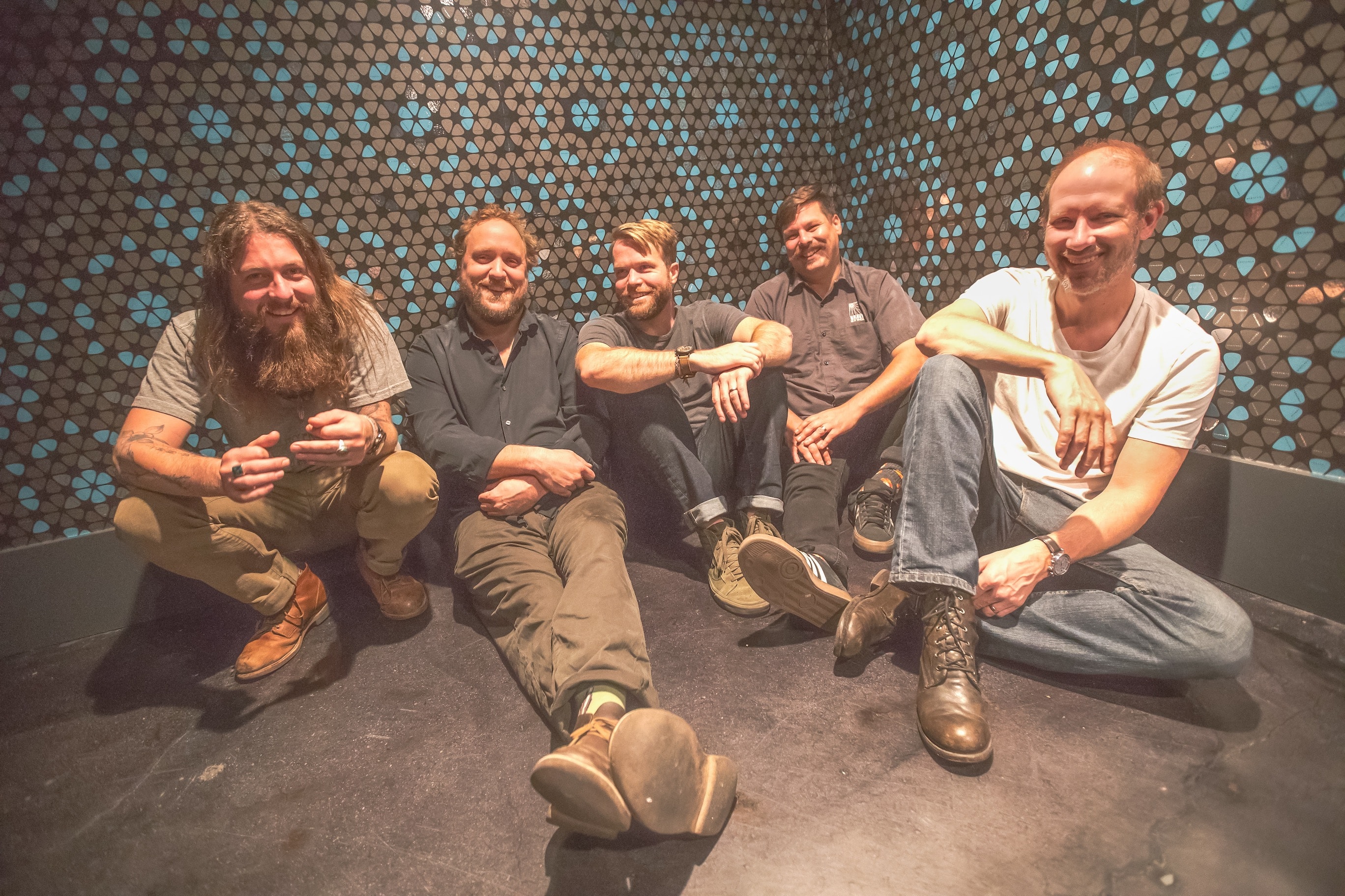 band sitting in front of mosaic wall