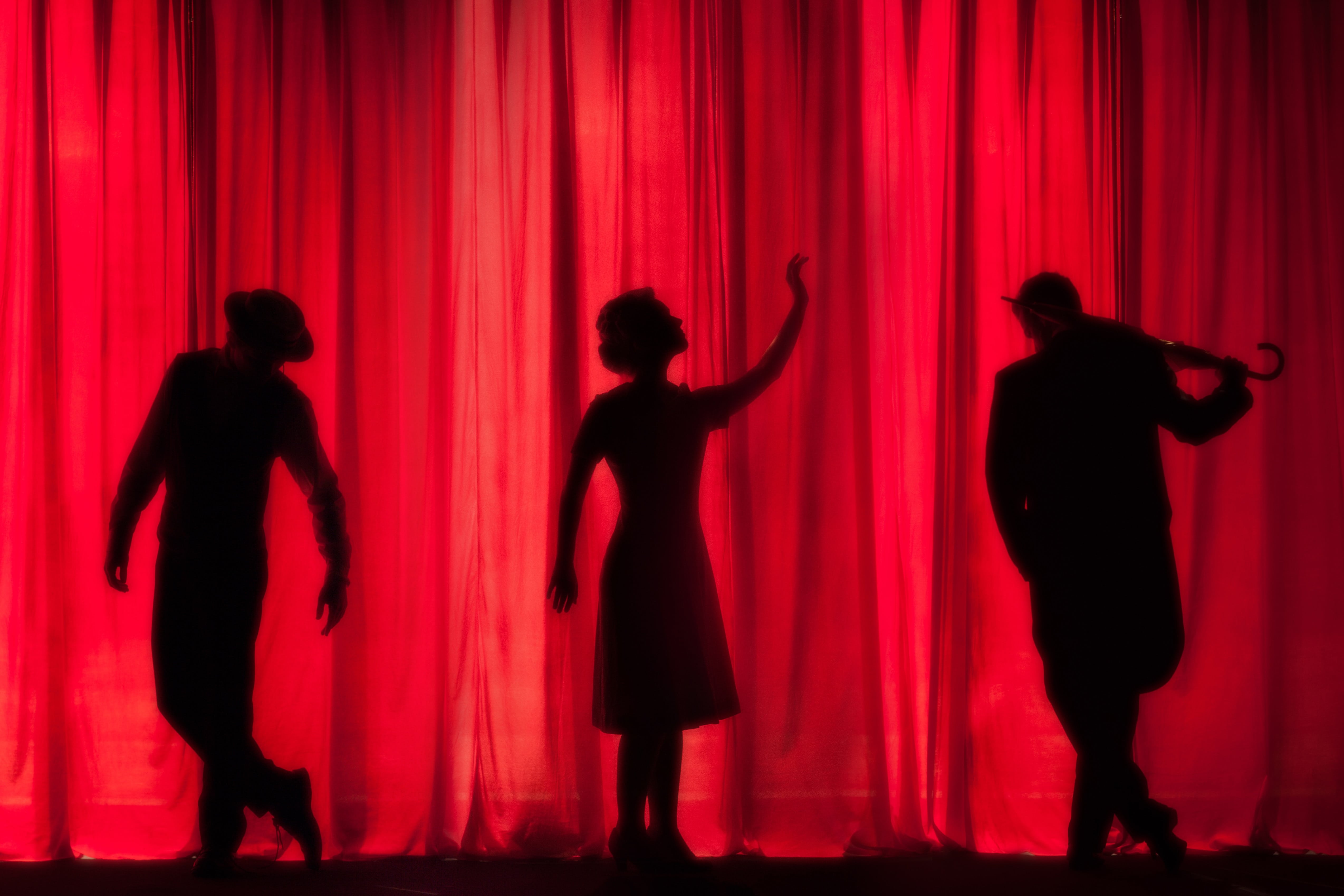 Three actors stand onstage and perform for an audience