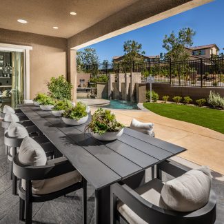 Luxury covered patio overlooking fenced backyard with small pool.