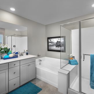 Bathroom with gray walls, a bath, and a glass door shower.