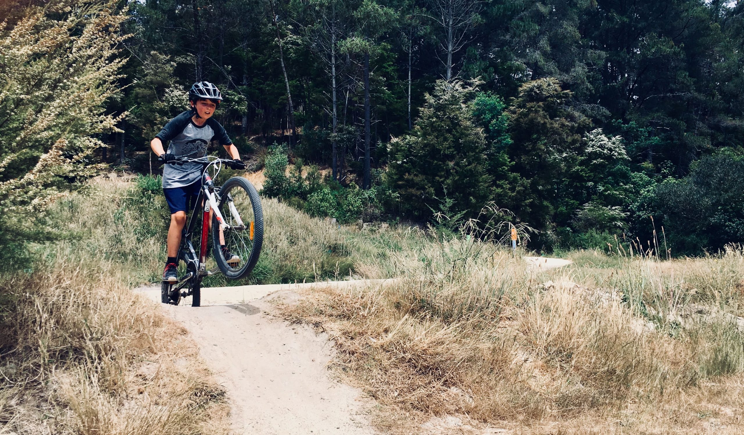 A boy rides his bike on a trail in the forest