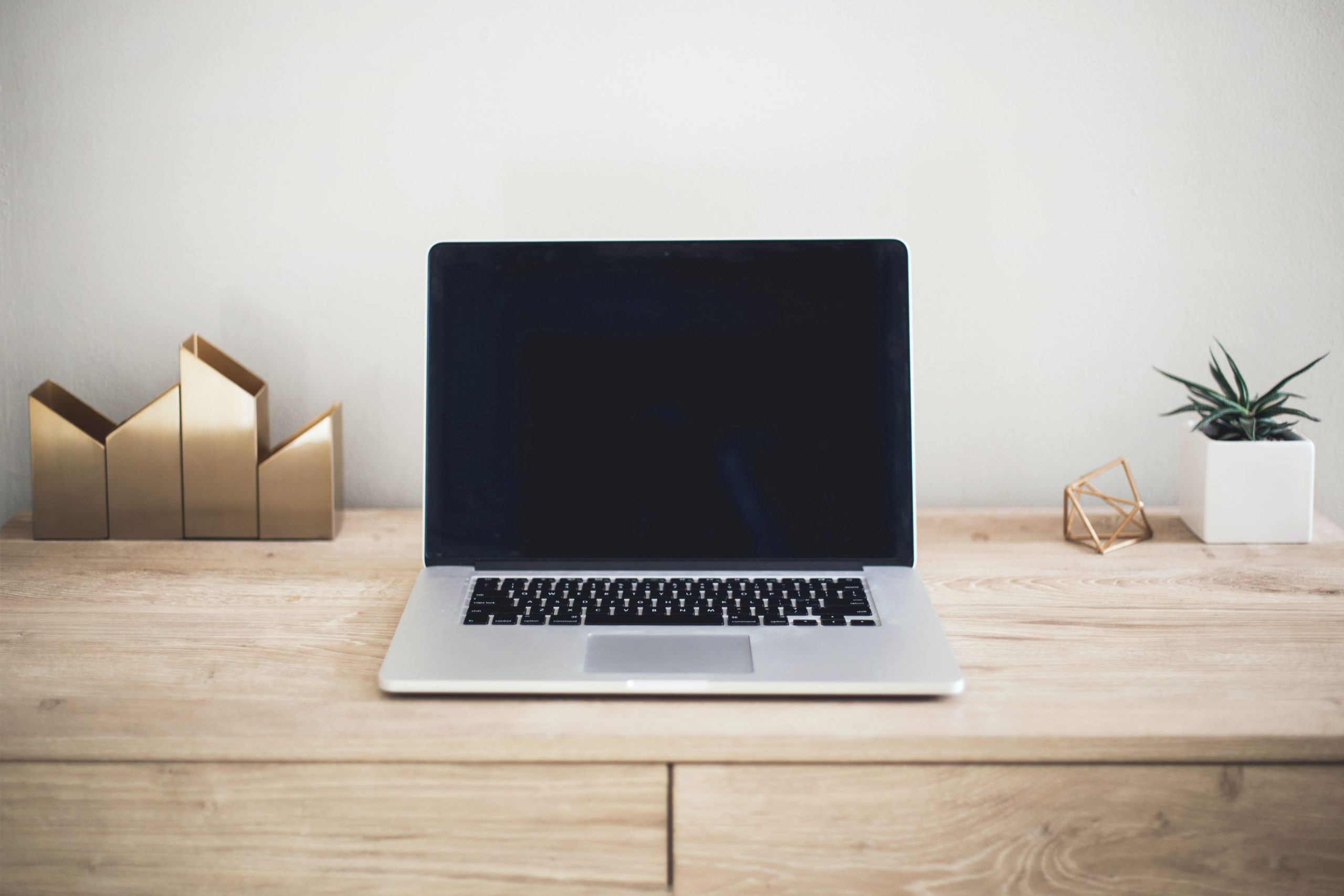 A silver laptop computer sits on a wooden desk.